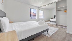 A bedroom with a bed, bedside table, and a large mirror. - Cozy Gainesville Apt • 2BR 2BA Stay near UF Campus (Gainesville)