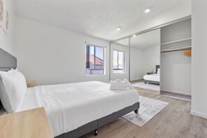 Quarto com cama, mesa de cabeceira e um espelho grande.
