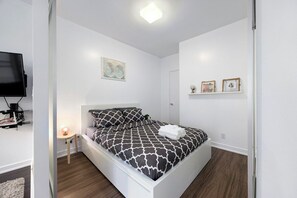 A bedroom with a bed, a bedside table, a lamp, and a television on a stand. - Stylish 1BR APT near DWTN with Balcony Views (Toronto)
