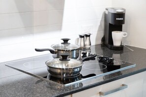 A modern kitchen with a black countertop, a stove, a coffee maker, and a pot on the induction cooktop. - Stylish 1BR APT near DWTN with Balcony Views (Toronto)