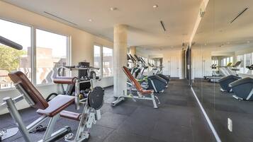 A modern gym with cardio machines, weight stations, and ample natural light.