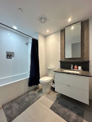Une salle de bain moderne équipée d’une baignoire, de toilettes et d’un meuble-lavabo.