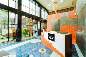 Un mostrador de recepción con un letrero que dice 'Townhouse Company Serviced' en un vestíbulo moderno con ventanas amplias y paneles de piedra y madera.