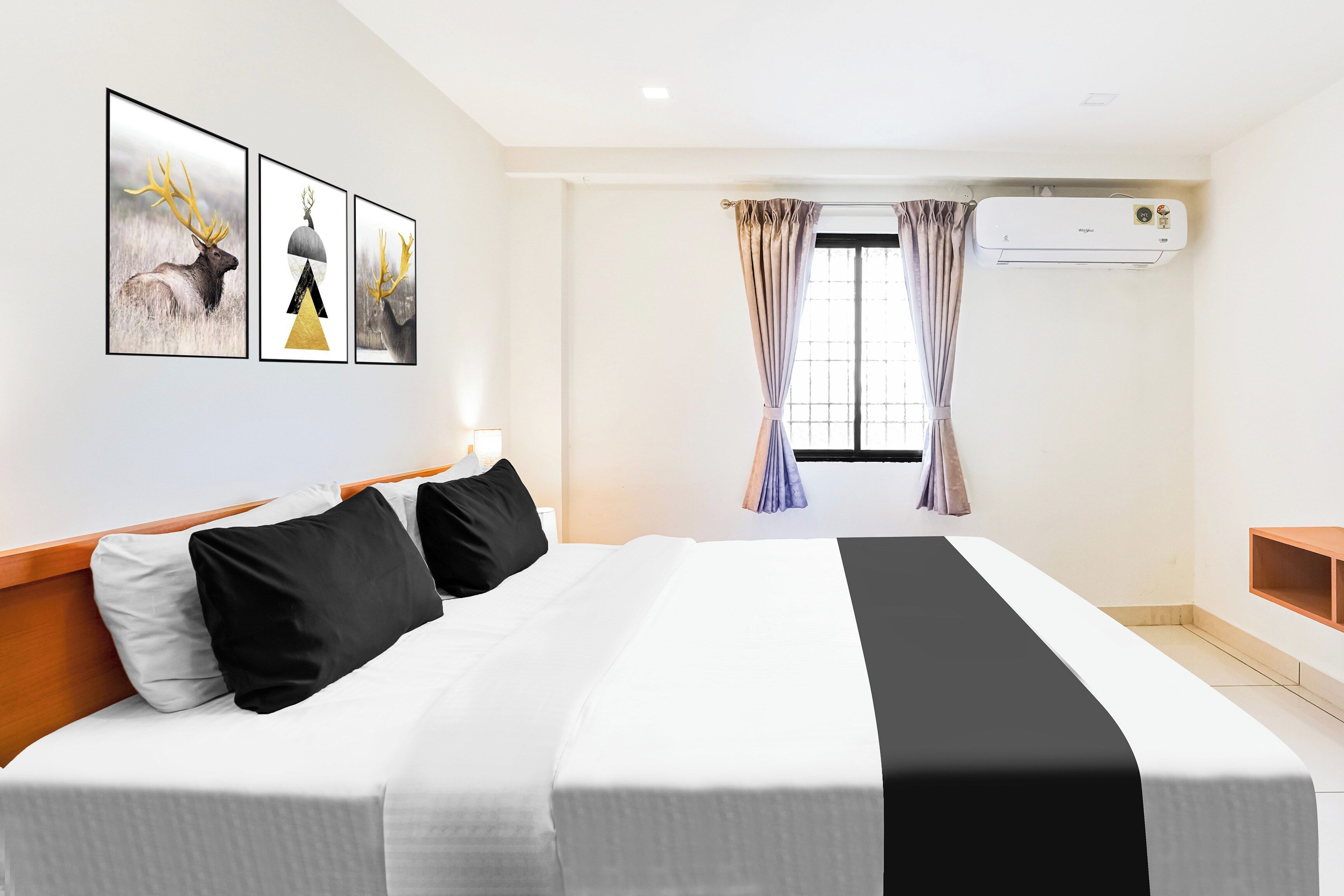 Ein Hotelzimmer mit einem großen Bett, einem fensterbelaubten Fenster, einer Klimaanlage und Wandbildern.