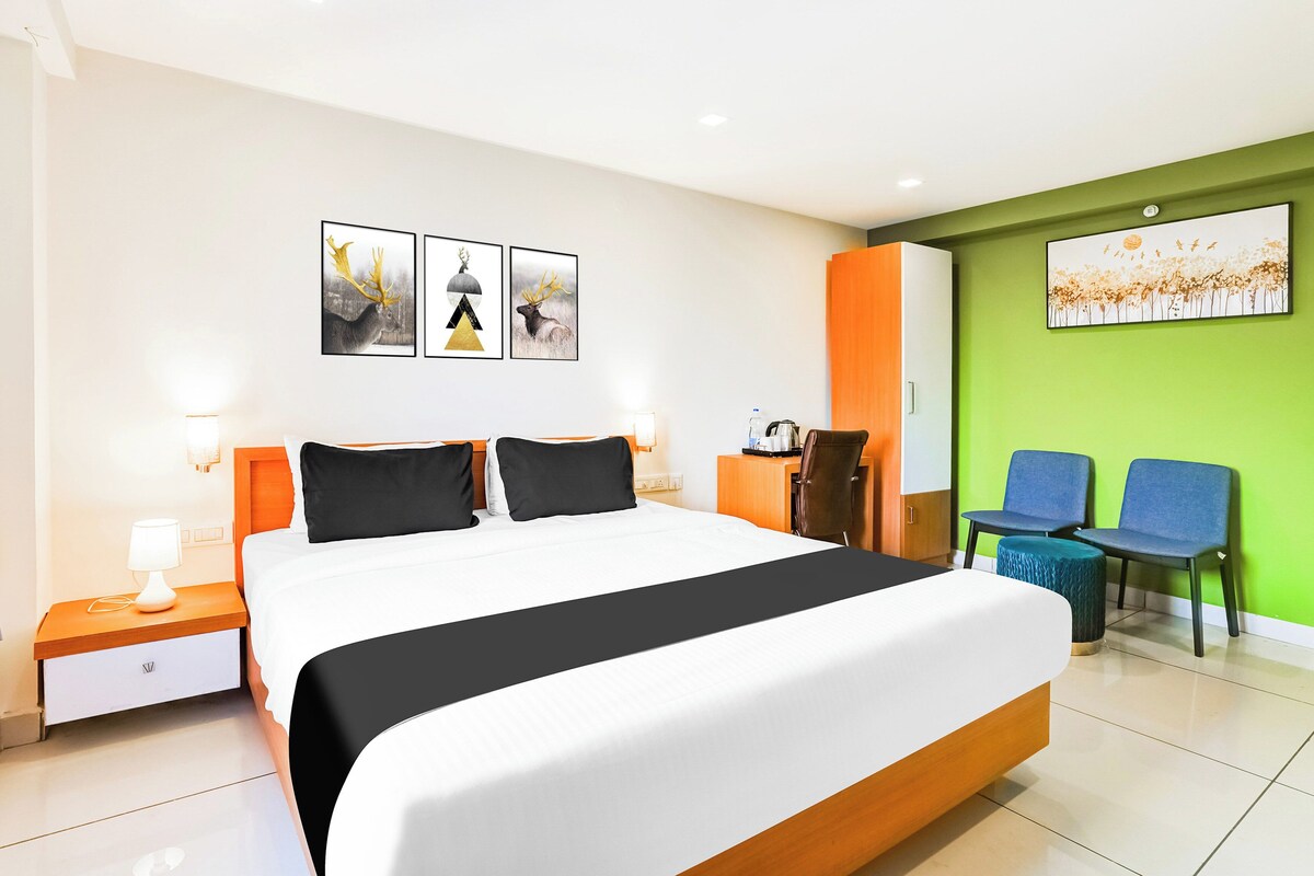 Una habitación de hotel con una cama grande, un escritorio, dos sillas y obras de arte en las paredes.