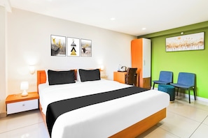 Una habitación de hotel con una cama grande, un escritorio, dos sillas y obras de arte en las paredes.