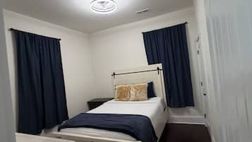 A small, narrow room with a bed, a desk, and a wardrobe.