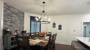 Uma área de refeições com mesa de madeira, cadeiras e luminária pendente.