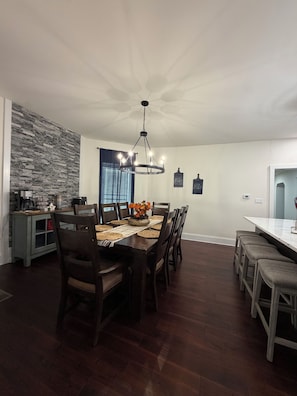 A dining area with a wooden table, chairs, and a hanging light fixture.