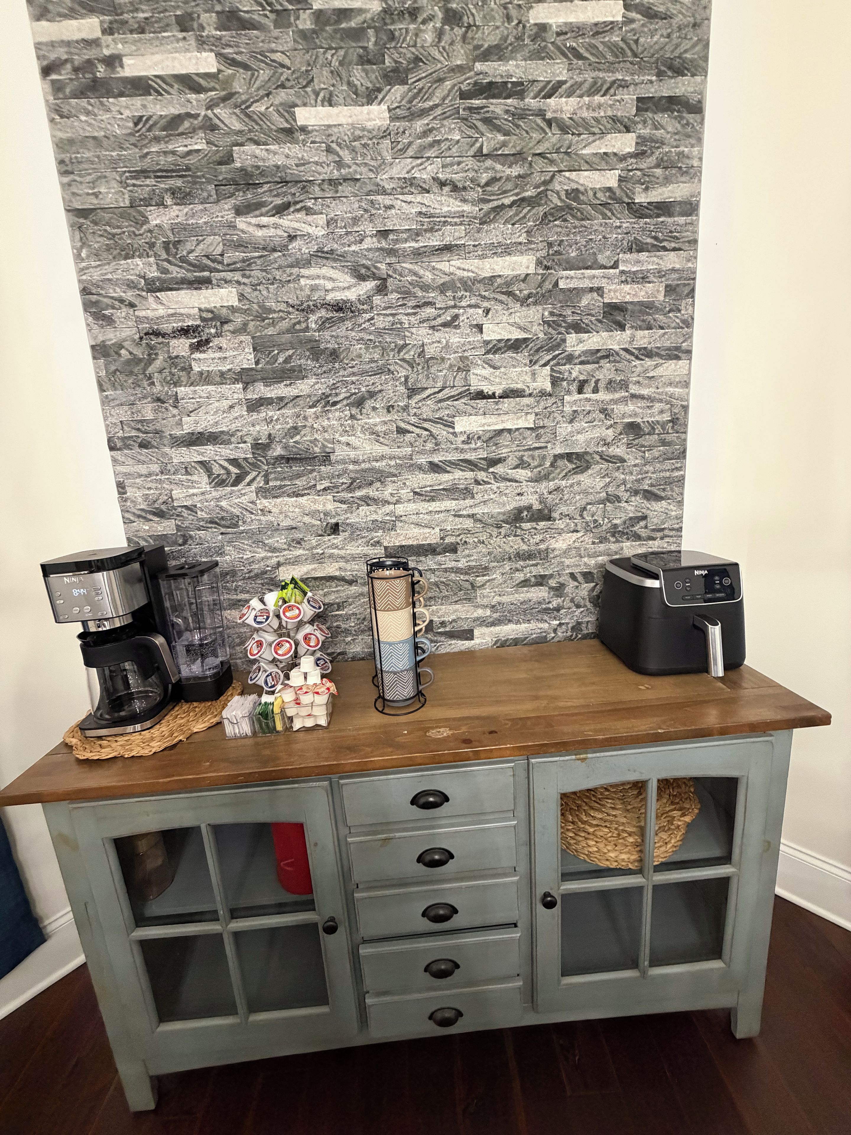 A kitchen counter with a coffee maker, a blender, and a mug holder.