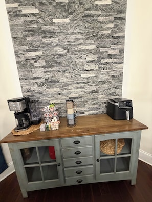 A kitchen counter with a coffee maker, a blender, and a mug holder.