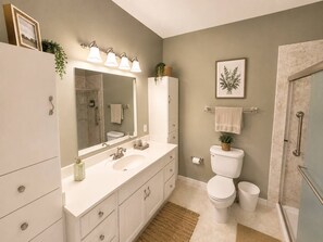 Ein Badezimmer mit einem Doppelwaschtisch, Toilette, Duschbereich und einem Handtuchhalter.