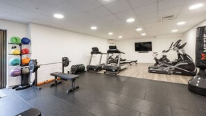 Ein Fitnessraum mit Laufbändern, einer Bank, Gewichte und einem Boxsack.