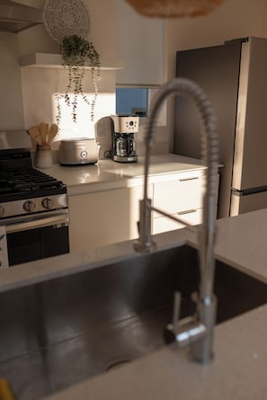 Eine Küche mit einem Edelstahl-Kühlschrank, einem Toaster und einem Spülbecken mit einem flexiblen Wasserhahn.