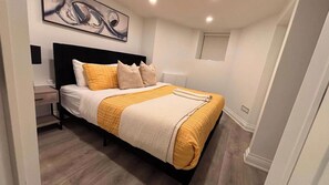 Quarto com cama, mesa de cabeceira e um quadro na parede.