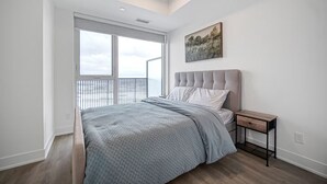 Quarto com cama grande, mesa de cabeceira, um quadro e vista do céu.