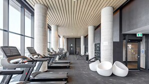 Uma academia com esteiras, aparelhos de musculação e amplas janelas.