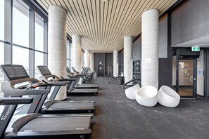Et fitnesscenter med løbebånd, styrkemaskiner og store vinduer.
