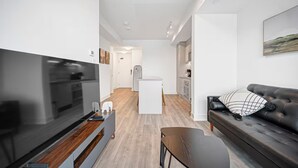 Uma sala de estar moderna com uma televisão de tela plana, um sofá e uma mesa de centro.