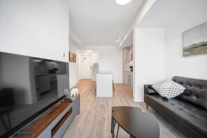 En moderne stue med et fladskærms-tv, en sofa og et sofabord.