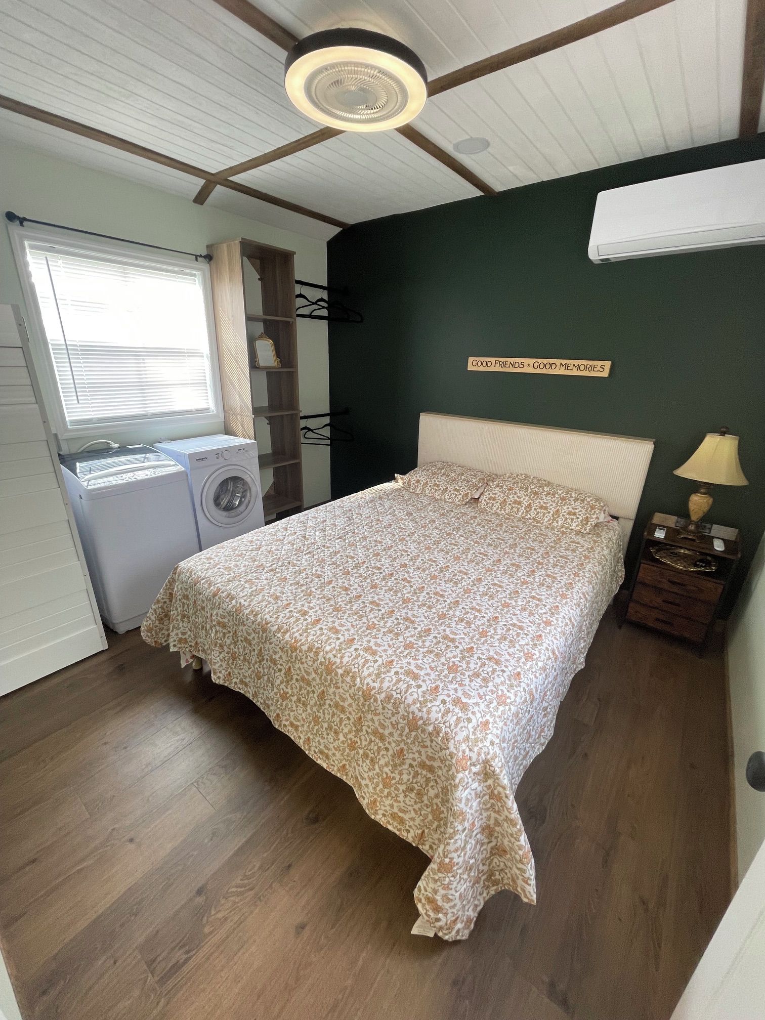 Une chambre avec un lit, un lave-linge, un étendoir et un radiateur fixé au mur.