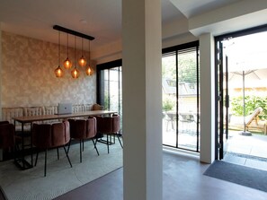 A modern dining area with a long table, multiple chairs, and pendant lighting. - Schoorl Villa With Fireplace (Schoorl)
