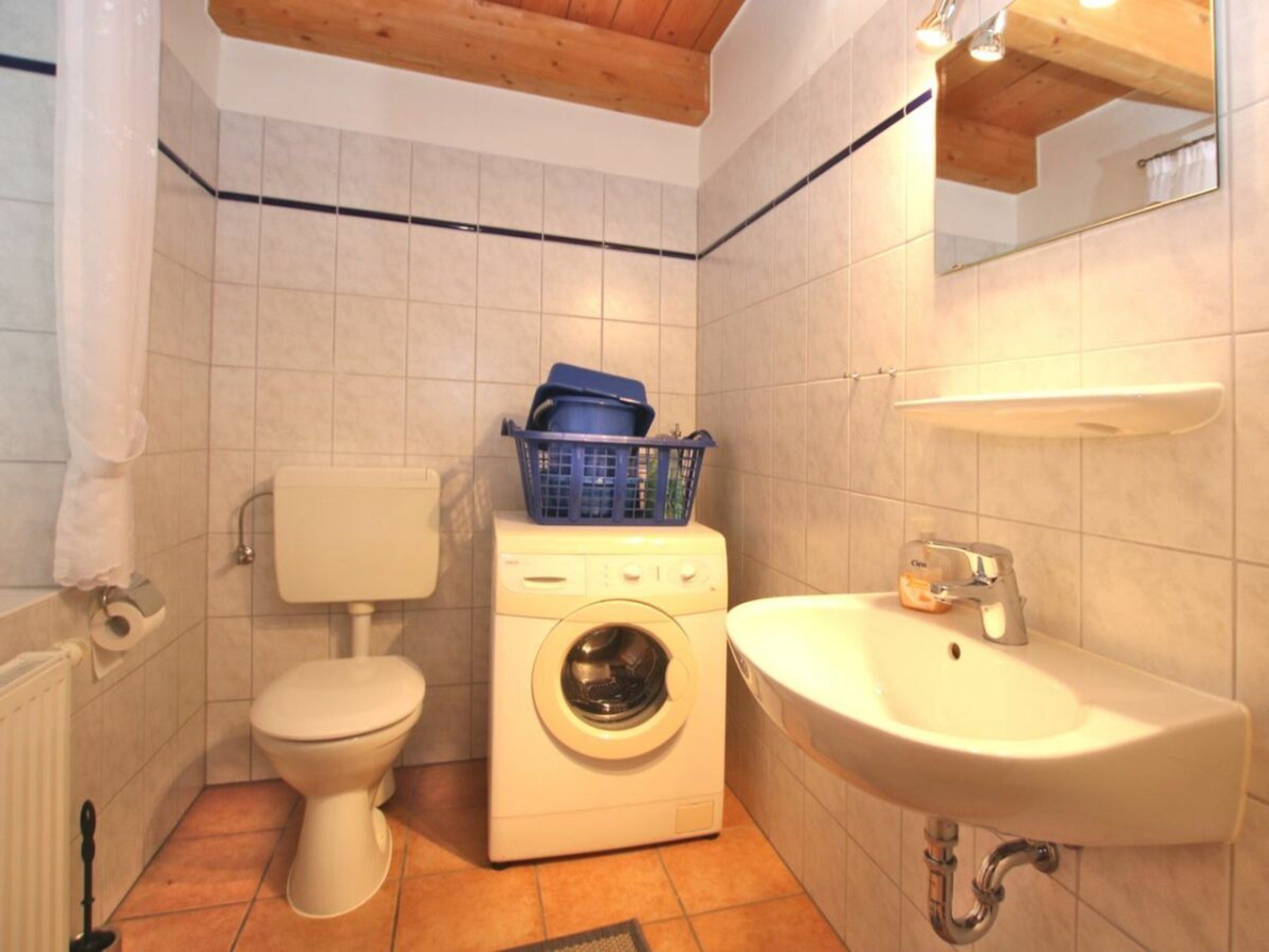 A compact bathroom with a toilet, washing machine, and sink.