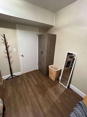 Una habitació amb terra de fusta, un armari, un mirall i un penjallabecs.