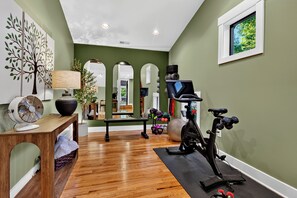 Una palestra in casa con attrezzature per esercizi, uno specchio e una ventola.