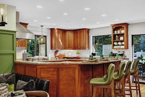 Una cucina moderna con mobili in legno, una grande isola con sgabelli da bar e vista all'esterno.