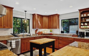 A modern kitchen with wooden cabinets, granite countertops, and a central island. - Wintergreen Luxury! Sleeps 18 with Hot Tub, Sauna, Arcades (Wintergreen Resort)