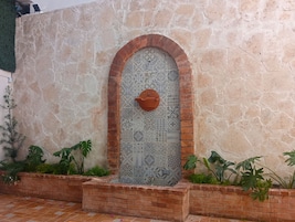 Un muro de piedra con una puerta azulejada, adornada con patrones geométricos y una maceta de terracota.