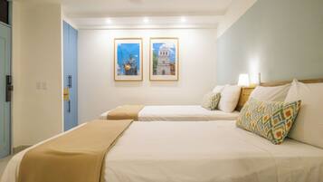 Une chambre d’hôtel avec deux lits, un ventilateur de plafond et deux tableaux encadrés accrochés au mur.
