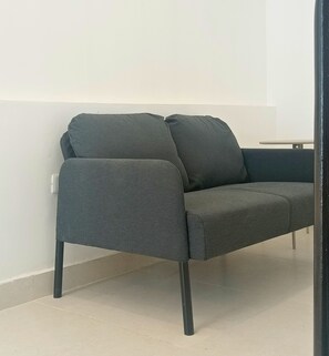 A grey sofa with a single armrest and a matching ottoman against a plain wall. - Meriño 556 Colonial Loft (Santo Domingo)