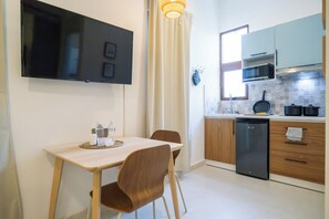 A modern kitchen with a flat-screen TV, a dining table with chairs, and a built-in oven. - Meriño 556 Colonial Loft (Santo Domingo)