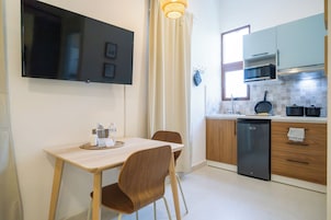 Una cocina moderna con un televisor de pantalla plana, una mesa de comedor con sillas y un horno empotrado.