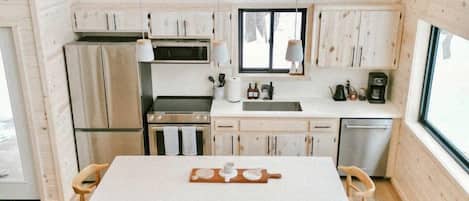 Una cocina moderna con armarios de madera, una isla central y un comedor con sillas.