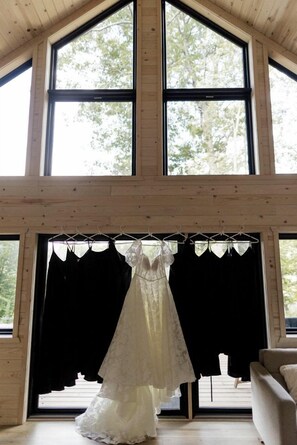 A room with large windows, a hanging dress, and a chair. - Tranquil Cabin Escape with Private Sauna & Kayak Fun in Mission Township, Minnesota (Mission Township)