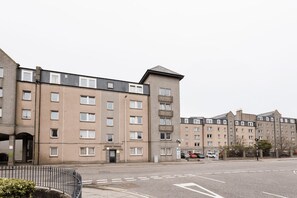 A multi-story residential building with a flat facade, multiple windows, and a parking area in front. - Student Only Spring Gardens (Aberdeen)