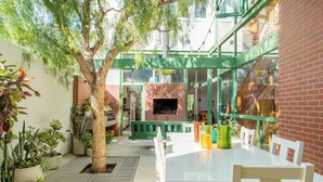 Eine moderne Außenpatio mit Kamin aus Ziegelsteinen, weißen Möbeln und Topfpflanzen.