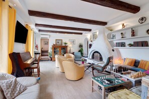 A spacious living room with a fireplace, a television, and a chessboard.