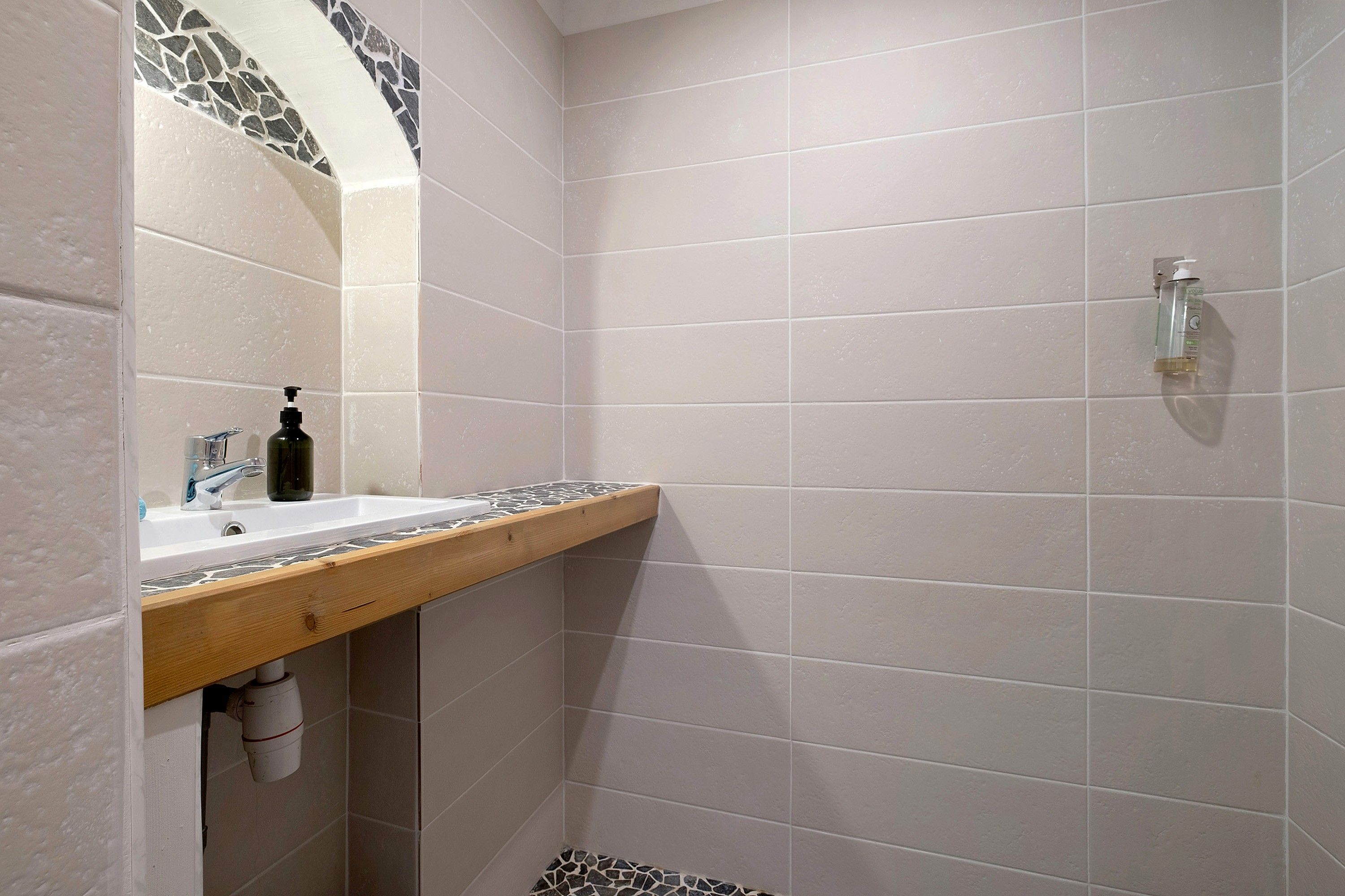 A bathroom with a sink, mirror, and shower.