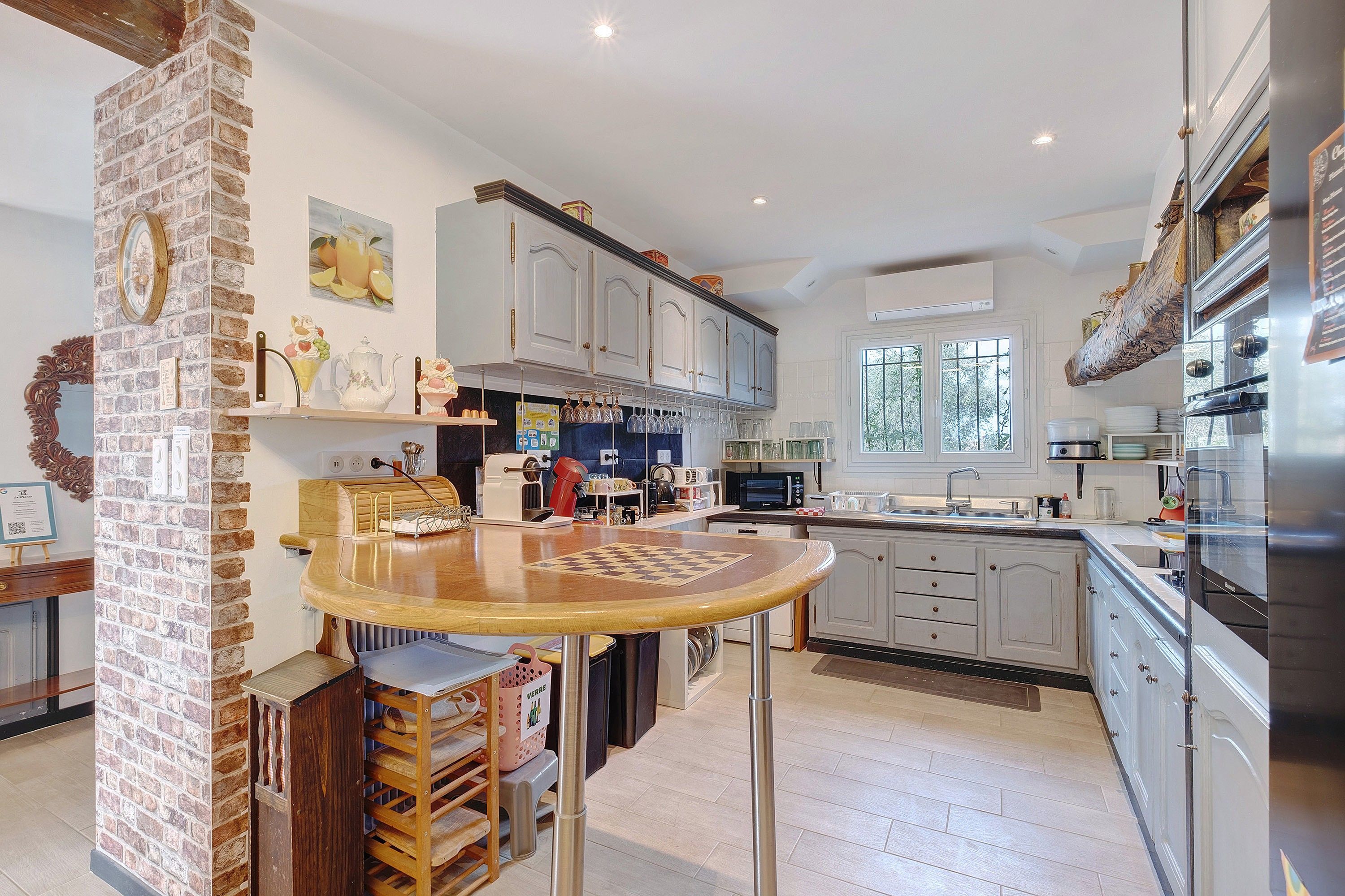 A kitchen with a brick column, wooden table, and modern appliances.