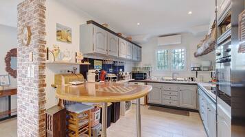 A kitchen with a brick column, wooden table, and modern appliances.
