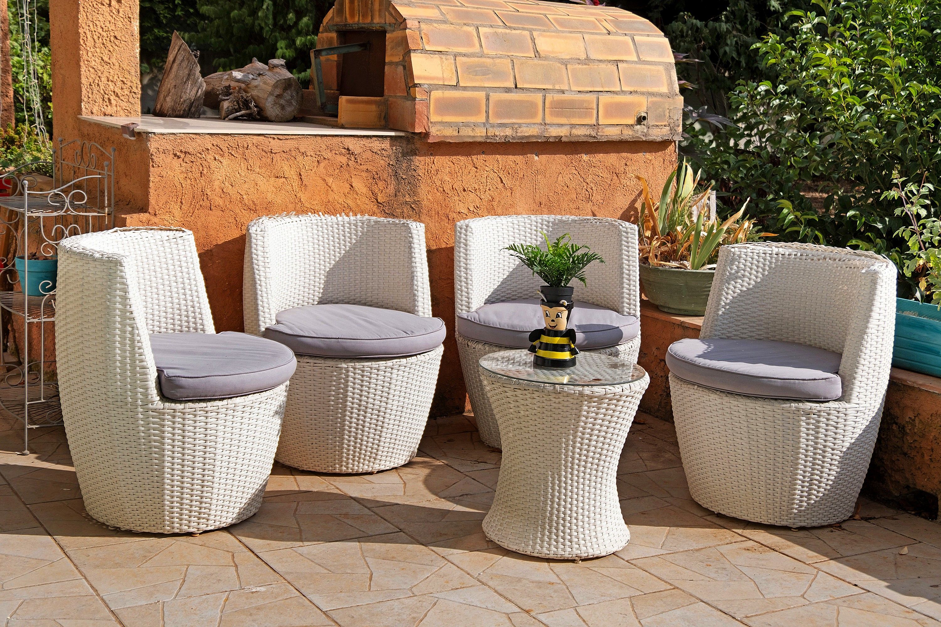 Un patio con mobiliario de mimbre y una pequeña mesa con un objeto decorativo.