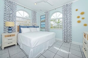 Una camera da letto con un letto, comodini, una lampada e vista sull'esterno attraverso le finestre.