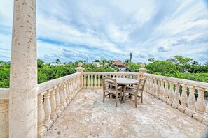 Ein Balkon mit Tisch und Stühlen, einer Brüstung und Blick auf Grünflächen sowie Gebäude im Hintergrund.
