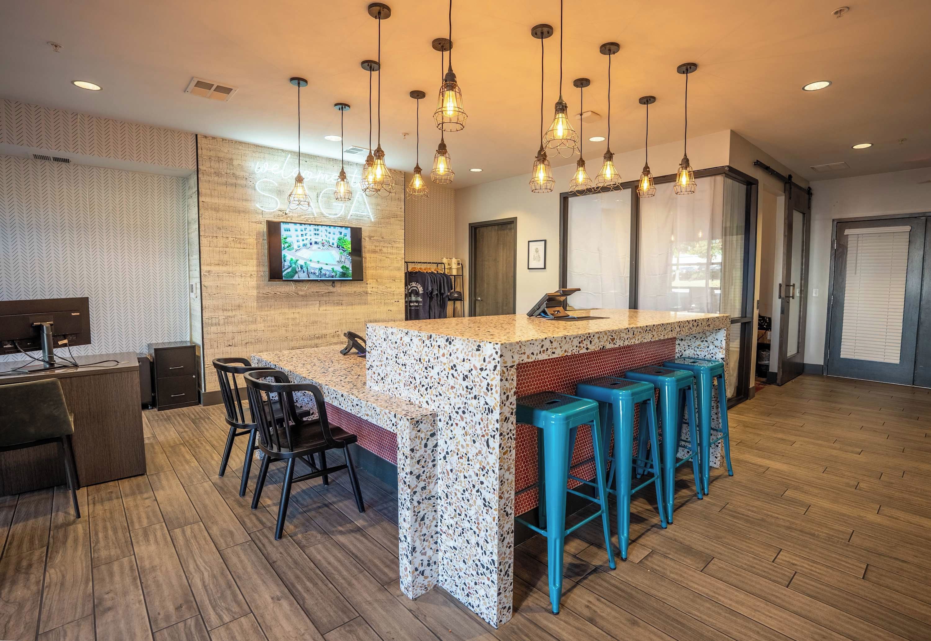 A bar area with a wooden counter, bar stools, and hanging pendant lights.
