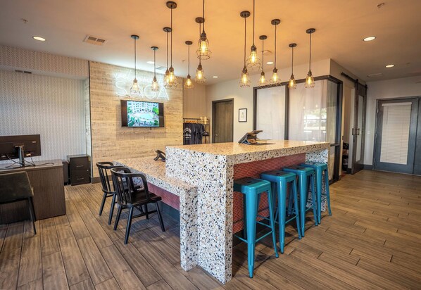 A bar area with a wooden counter, bar stools, and hanging pendant lights.