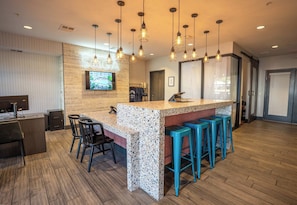 A bar area with a wooden counter, bar stools, and hanging pendant lights. - Balcony Retreat Near USC, The Vista & Downtown (Columbia)